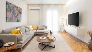 Ein modernes Wohnzimmer mit einer Couch, einem Couchtisch und einem Flachbildfernseher.
