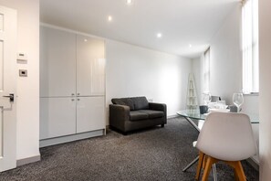 Relax in this stylish space with a glass dining table, comfortable sofa, and ample storage.