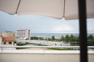 Vista desde un balcón con vista a la costa, edificios, una carretera y una masa de agua.