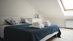 A bedroom with a bed, pillows, a blue blanket, and a stack of towels. - Cucci House Lido Riccio (Ortona)