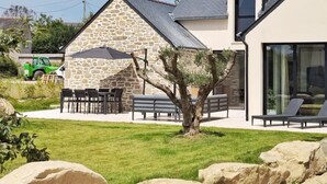 Ein Steinhaus mit Terrasse, Sitzgelegenheit im Freien und einem Rasen.