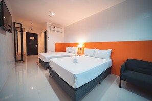 Een hotelkamer met twee bedden, een bank en een aan de muur bevestigde televisie.