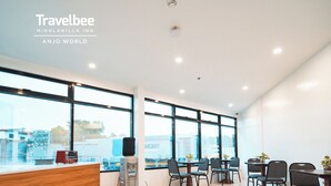 Eine moderne Hotelhalle mit einer Rezeption, einer Sitzecke und großen Fenstern mit Blick auf die Stadt.