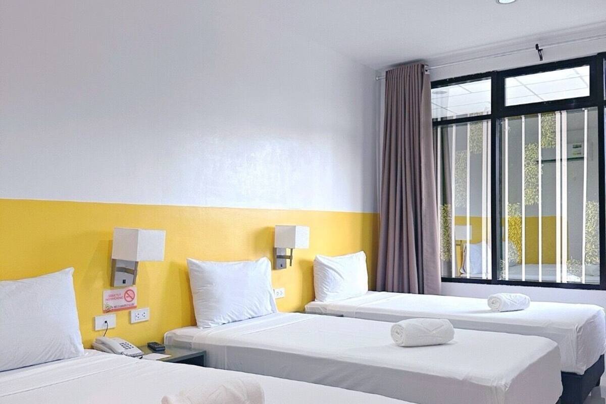 Une chambre d’hôtel avec deux lits, un téléphone et une fenêtre avec des rideaux.