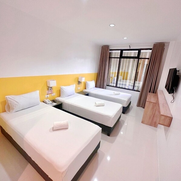 A hotel room with two beds, a desk, a TV, and a window with curtains. - Travelbee Minglanilla Inn (Minglanilla)