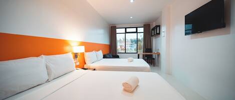 Habitación de hotel con dos camas, televisión, escritorio y ventana con cortinas.