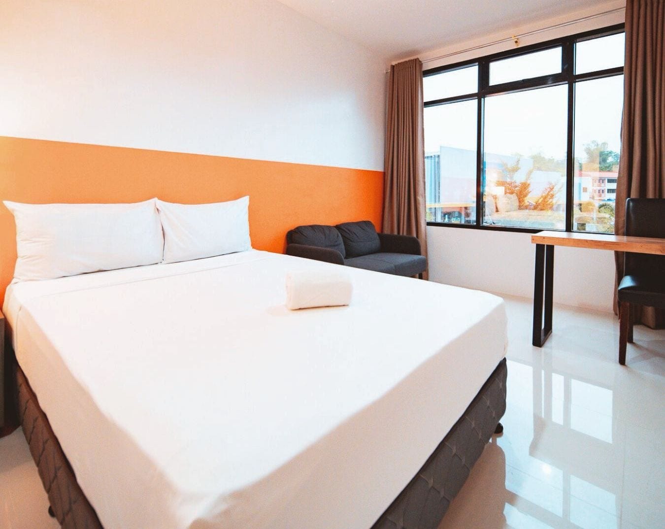 Habitación de hotel con una cama grande, un escritorio y una ventana con cortinas.