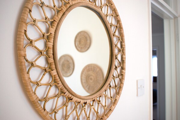 Un miroir mural doté d’un cadre tressé.