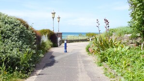 A paved pathway leading to a coastal area with a fence, lamp posts, and lush greenery. - Family Seaside Bungalow - Max 6 Adults Only - 2 Small -Medium Sized Dogs Welcome - Nr Beach (Margate)