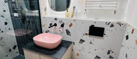 A bathroom with a pink basin, a toilet, and a shower area.