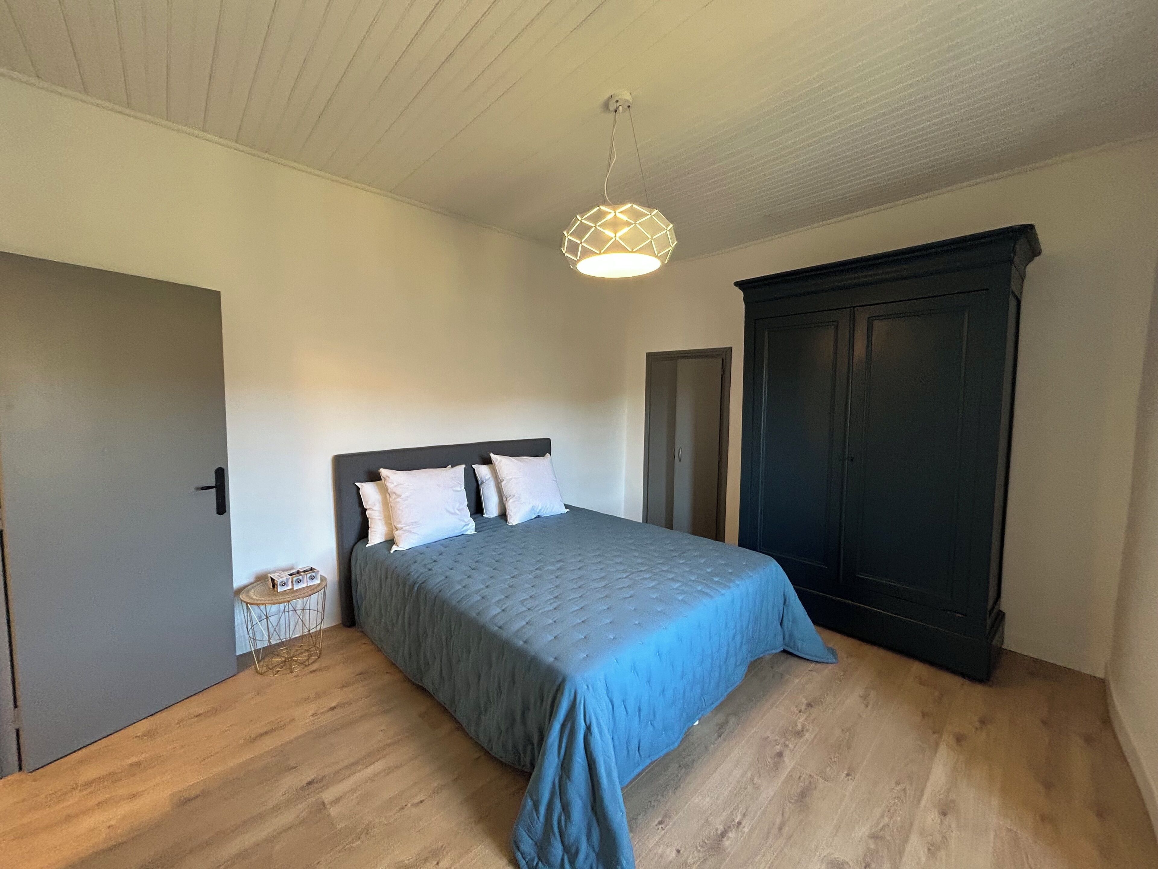 A bedroom with a bed, a wardrobe, and a small round table.