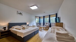 A modern bedroom with two beds, a TV, and a small table. - Appartement Traumblick (Bad Hofgastein)
