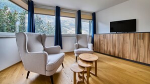 A modern room with two armchairs, a small wooden table, and a TV on a wooden cabinet. - Appartement Traumblick (Bad Hofgastein)