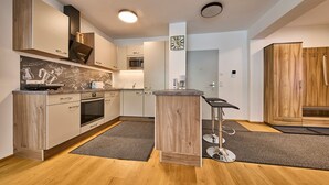 A modern kitchen with wooden cabinets, a central island, a microwave, and a coffee maker. - Appartement Traumblick (Bad Hofgastein)