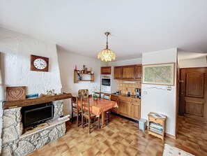 Cozy kitchen and dining area with oven, sink, and stone fireplace.