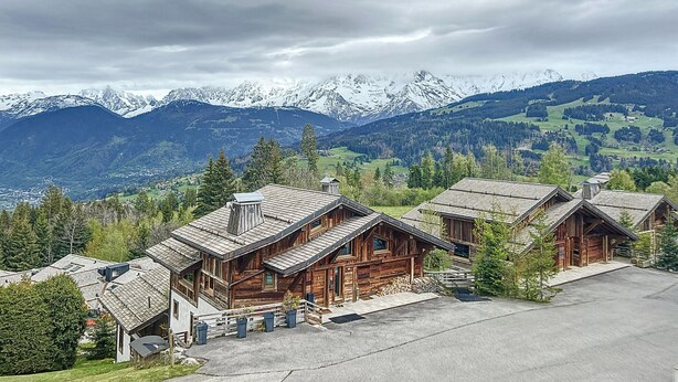 A wooden cabin complex with a paved driveway and a view of snow-capped mountains. - Cozy studio at the foot of the slopes with parking in Combloux (Combloux)