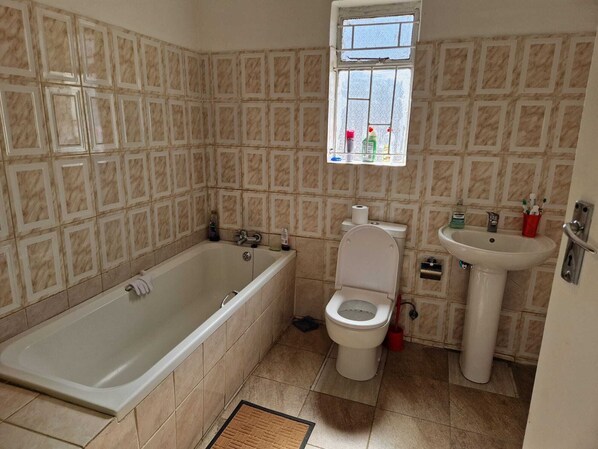 A bathroom with a bathtub, toilet, and sink, tiled with a geometric pattern.