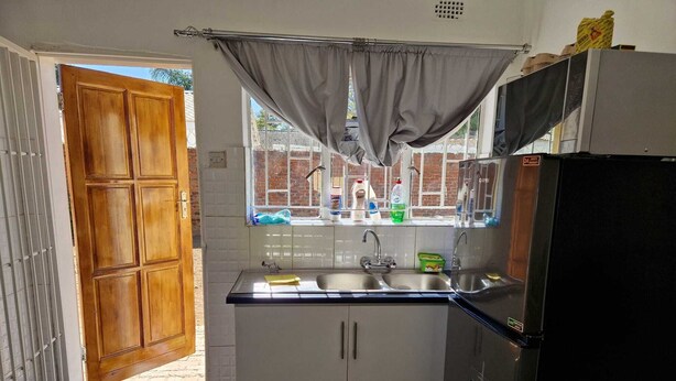 Een kleine keuken met een raam, een spoelbak en een koelkast.