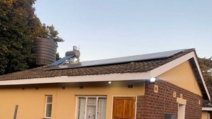 Een gelijkvloers huis met een bakstenen gevel, een gele buitenkant en een pannendak.