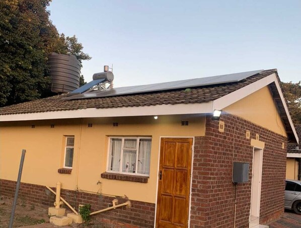 Situated in a residential area, this charming home features a central door, a small window above, and a visible chimney.