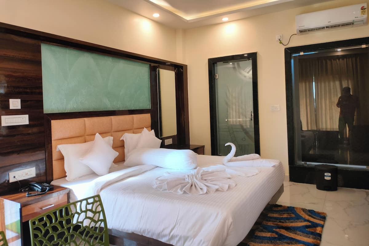 Ein Hotelzimmer mit einem großen Bett, einem Nachttisch mit Telefon, einem Spiegel und einer Klimaanlage.