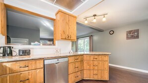 A modern kitchen with wooden cabinets, a dishwasher, and a countertop with a toaster.