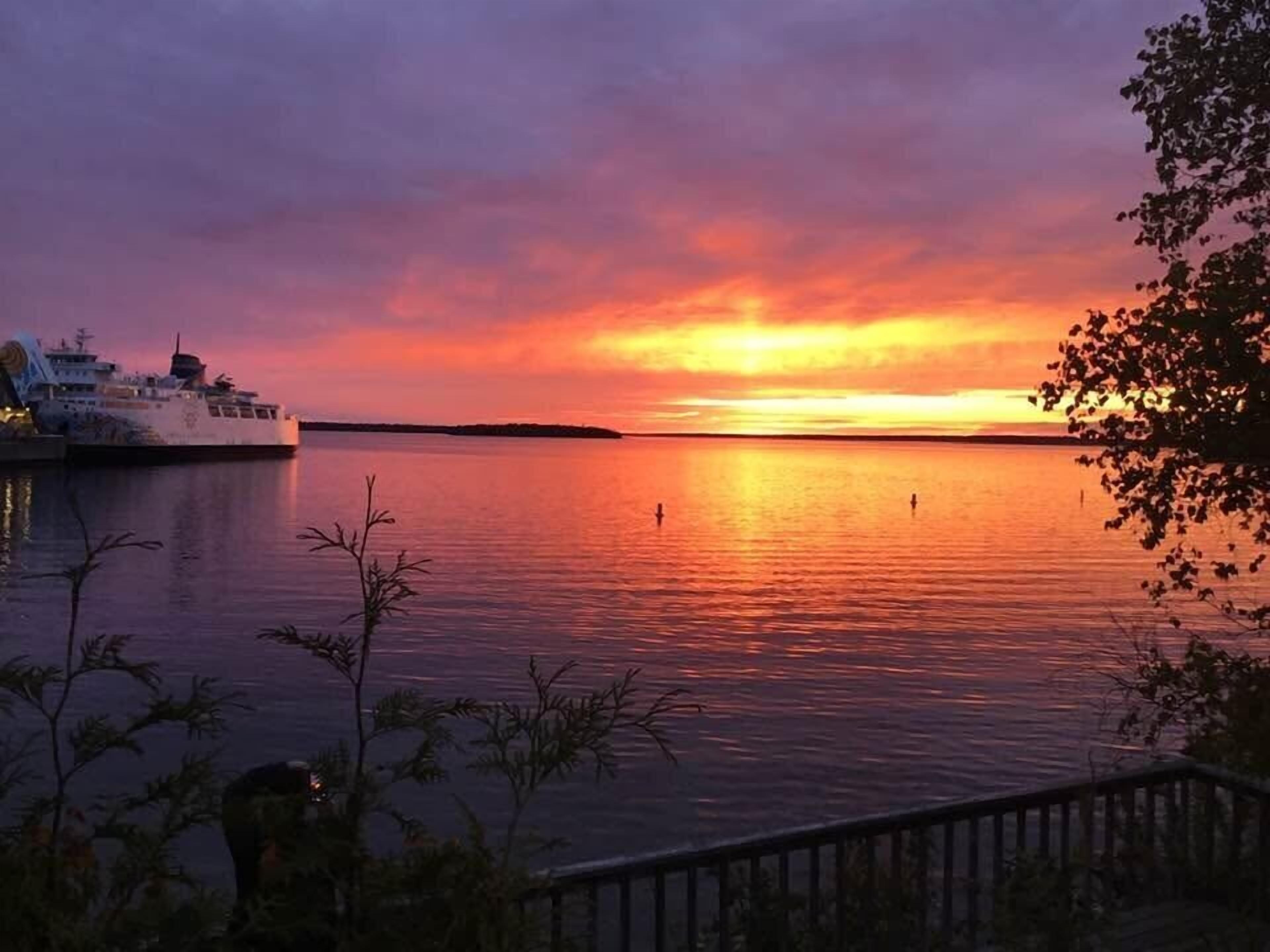Un atardecer sobre aguas tranquilas con un barco amarrado a la izquierda.
