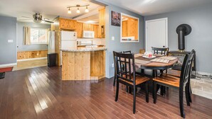 A spacious kitchen with wooden cabinets, a central island, and a dining area with a round table and chairs.