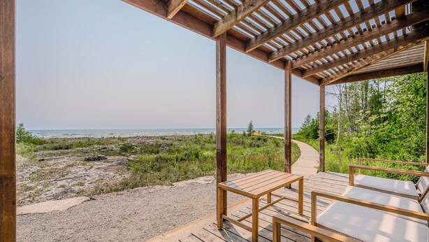 Terraza de madera con mesa y sillas con vistas a la playa.
