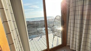 Una habitación con un gran ventanal corredero que da a un balcón con vistas al mar.