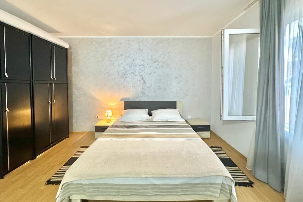 Una camera da letto con un letto, un comodino, una lampada, un armadio e una finestra con tende.