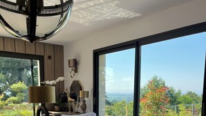 Ein modernes Wohnzimmer mit einem großen Esstisch, einer Couch und Blick ins Freie.