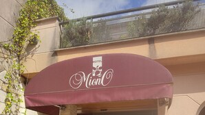 A hotel entrance with a maroon awning, a stone facade, and a blue 'H' sign indicating the hotel. - Hotel Suite Mioño Castro  (Castro Urdiales)
