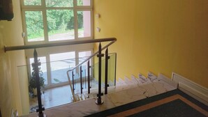 A staircase with a glass railing, a yellow wall, and a view of greenery outside. - Hotel Suite Mioño Castro  (Castro Urdiales)