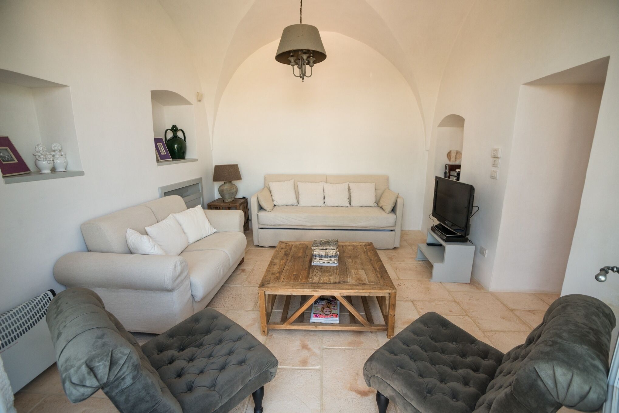 A living room with a beige sofa, a wooden coffee table, and two grey armchairs.