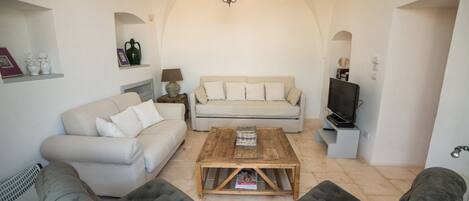 A living room with a beige sofa, a wooden coffee table, and two grey armchairs.