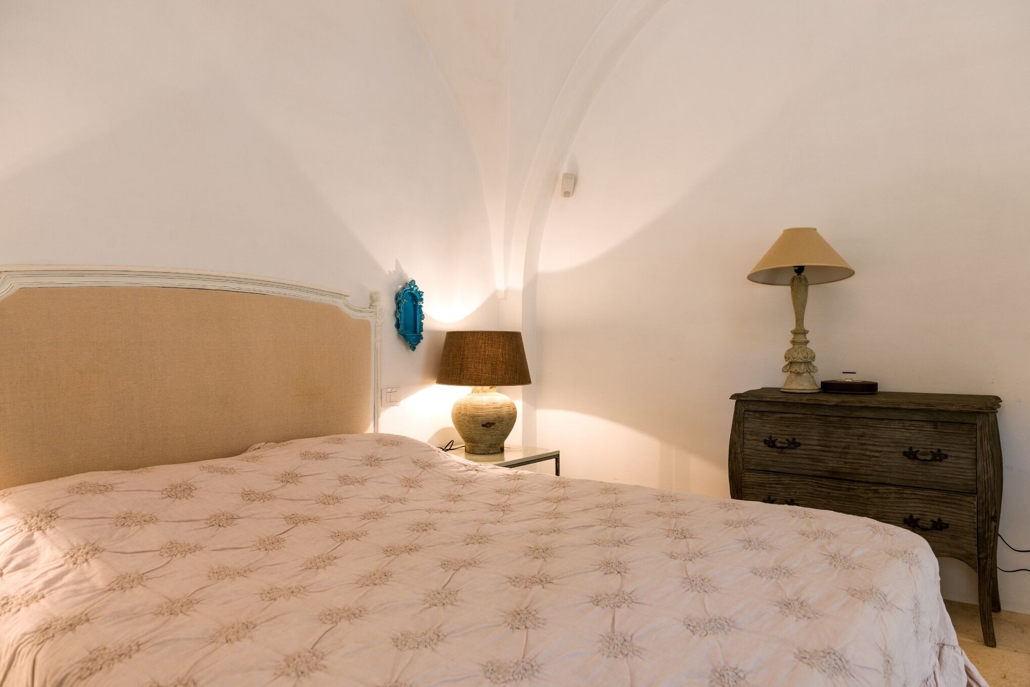 Une chambre à coucher avec un lit, une table de chevet avec une lampe et une commode.