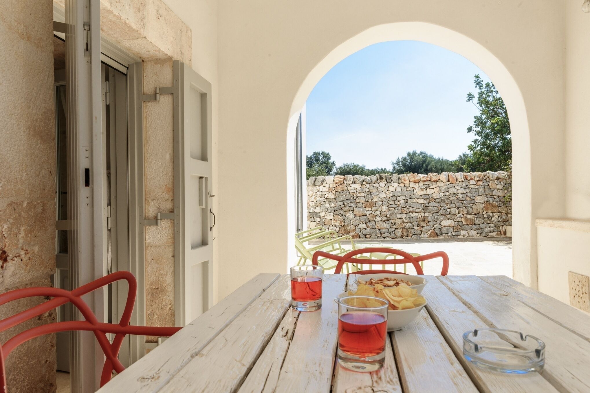 Un'area pranzo esterna rustica con un muro in pietra e una vista aperta sul cielo.