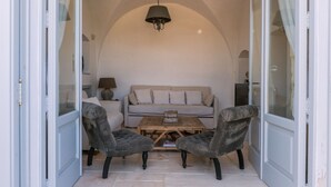 A cozy room with a sofa, two armchairs, a coffee table, and a chandelier. - Masseria Pepenofio (Monopoli)