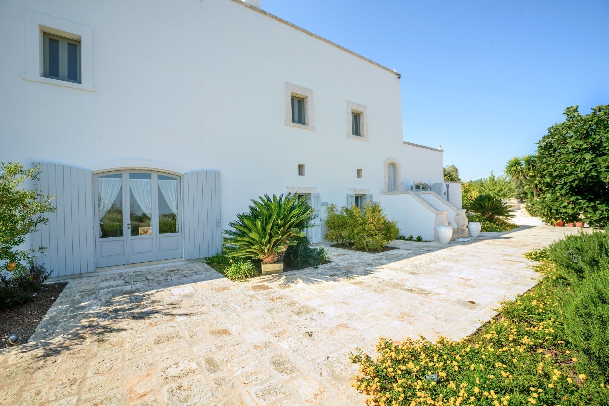 A white building with a stone pathway leading to a door with curtains.