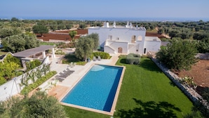 A large white villa with a swimming pool, surrounded by lush greenery and olive trees. - Masseria Pepenofio (Monopoli)