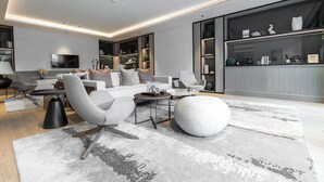Un salon moderne avec un canapé, des fauteuils, une table basse et un grand pouf blanc.
