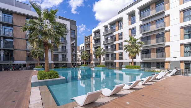Un hôtel moderne doté d’une piscine centrale, de nombreux balcons et d’espaces extérieurs aménagés pour se détendre.