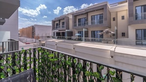 Un immeuble résidentiel moderne doté de nombreux balcons, d’une terrasse sur le toit et offrant une vue sur le ciel.