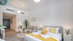 Une chambre d’hôtel moderne avec un grand lit, un coin salon avec un canapé, une petite table et une plante en pot.