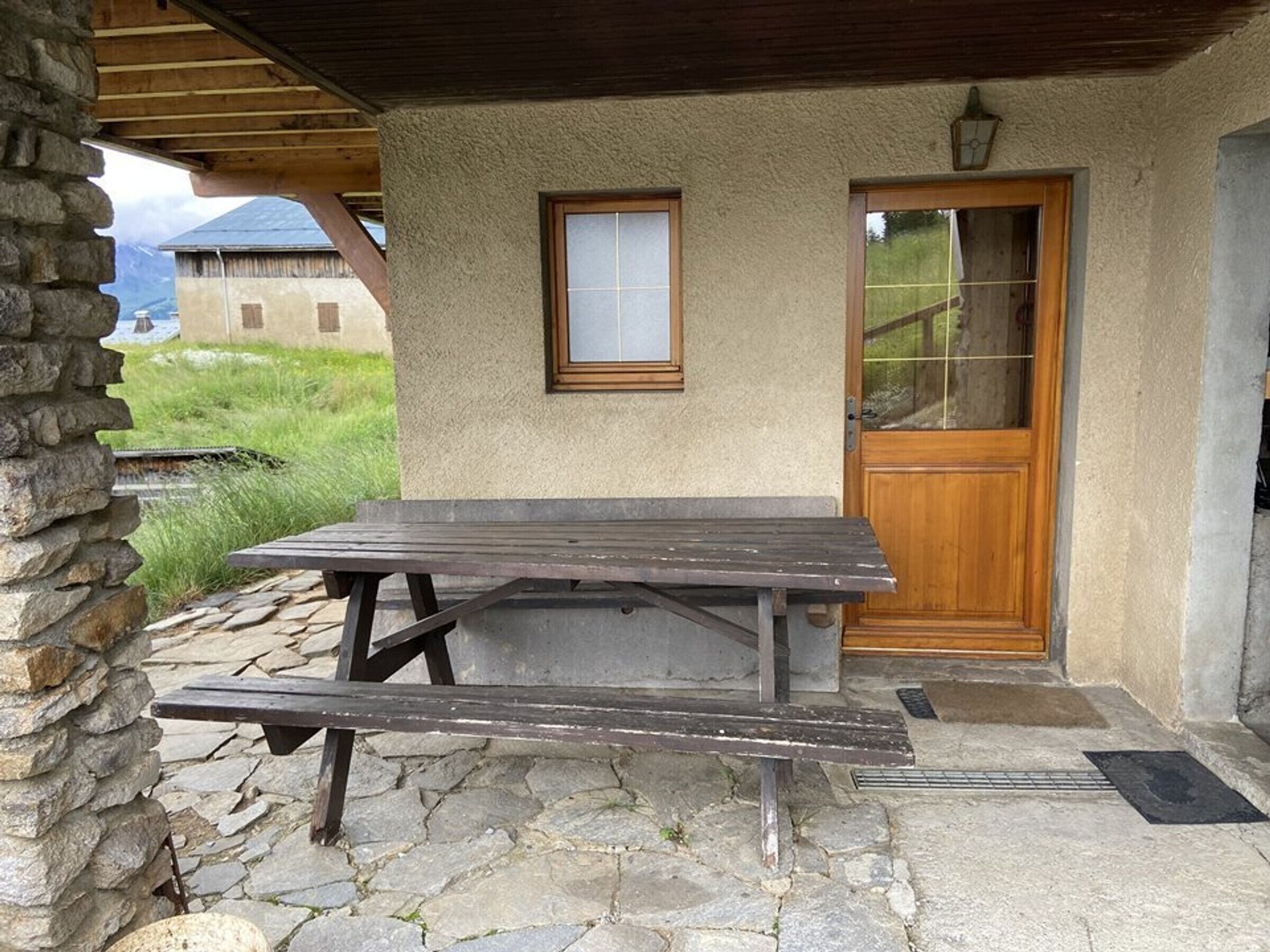 A stone patio with a wooden picnic table and a door with a window.