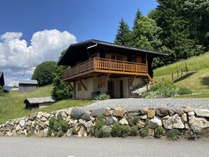 A chalet-style house with a wooden balcony, stone foundation, and a ski lift in the background. - Charming Chalet for 6 with Modern Amenities in Crest-Voland (Crest-Voland)