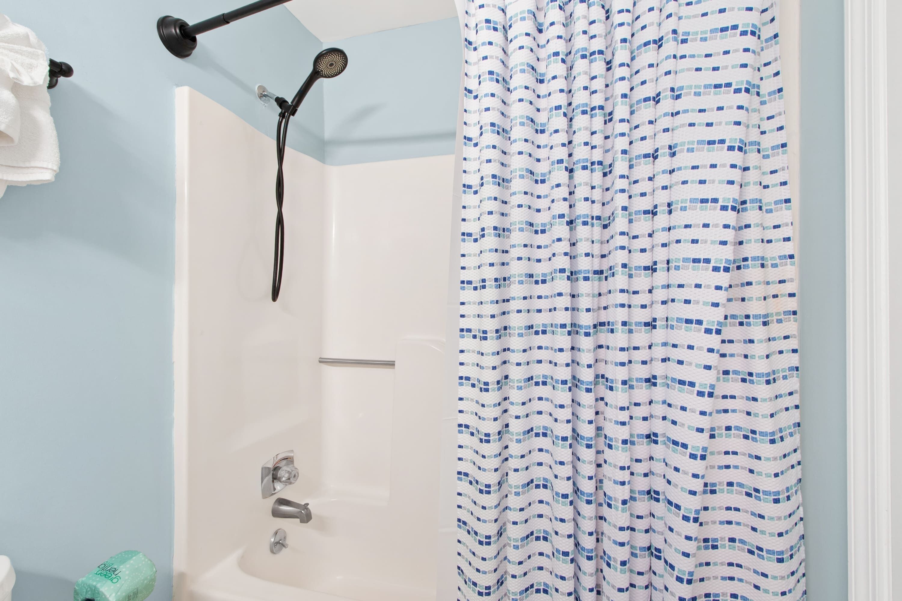 A bathroom with a shower, a towel rack, and a curtain.