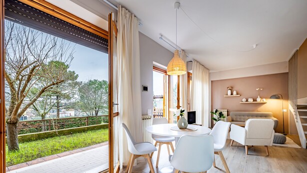 A modern living room with a dining area, large windows, and a view of the outdoors.