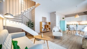 A modern living room with a staircase, a dining area, and a kitchen.
